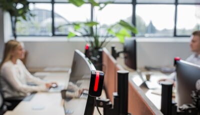GoBright - Hardware - Glow - Desk occupation status | A modern open-plan office with employees working at reserved desks, showing a coordinated hybrid workplace environment.