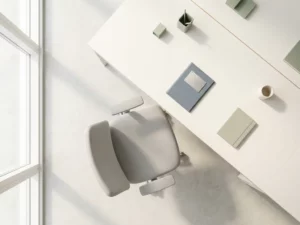Une chaise ergonomique devant un bureau minimaliste, dans un bureau ouvert et lumineux, une plaque nominative retournée, une douce lumière naturelle se reflétant sur des surfaces claires.